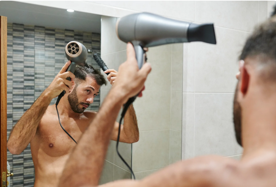 Man using a hair dryer correctly to prevent heat damage