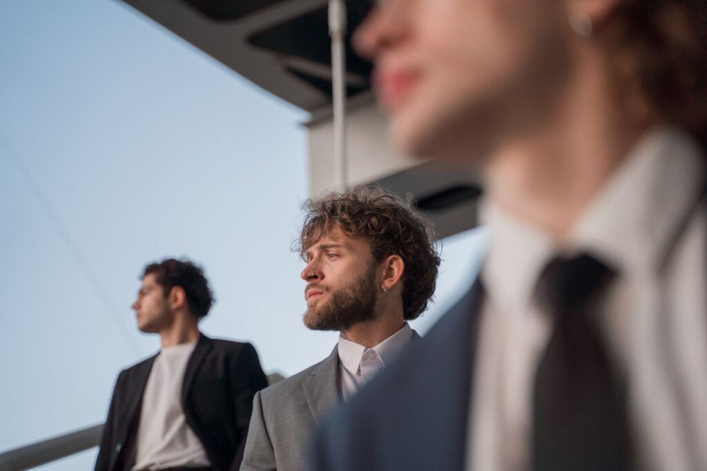 Three men in suits with diverse expressions outdoors against a modern backdrop.