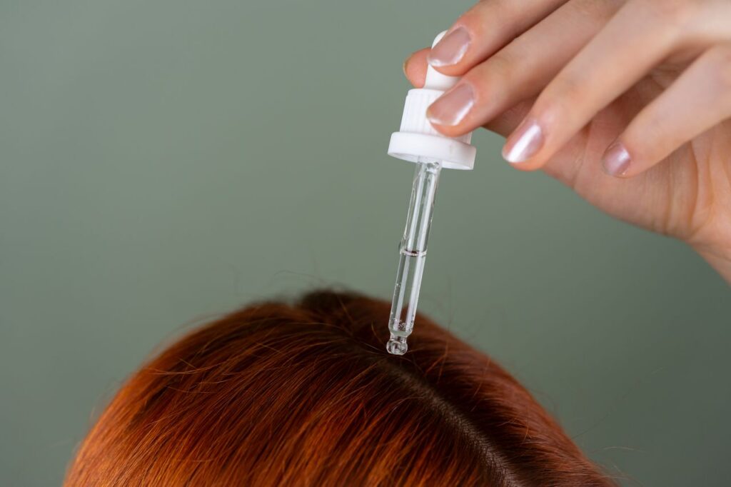 pexels-photo-28994390-28994390-2 Close-up of applying serum to roots with a precision dropper on red hair, showcasing hair care routine.