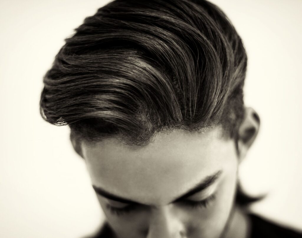 pexels-photo-4850600-4850600 Close-up portrait of a fashionable man showcasing a sleek hairstyle in a black and white studio shot.