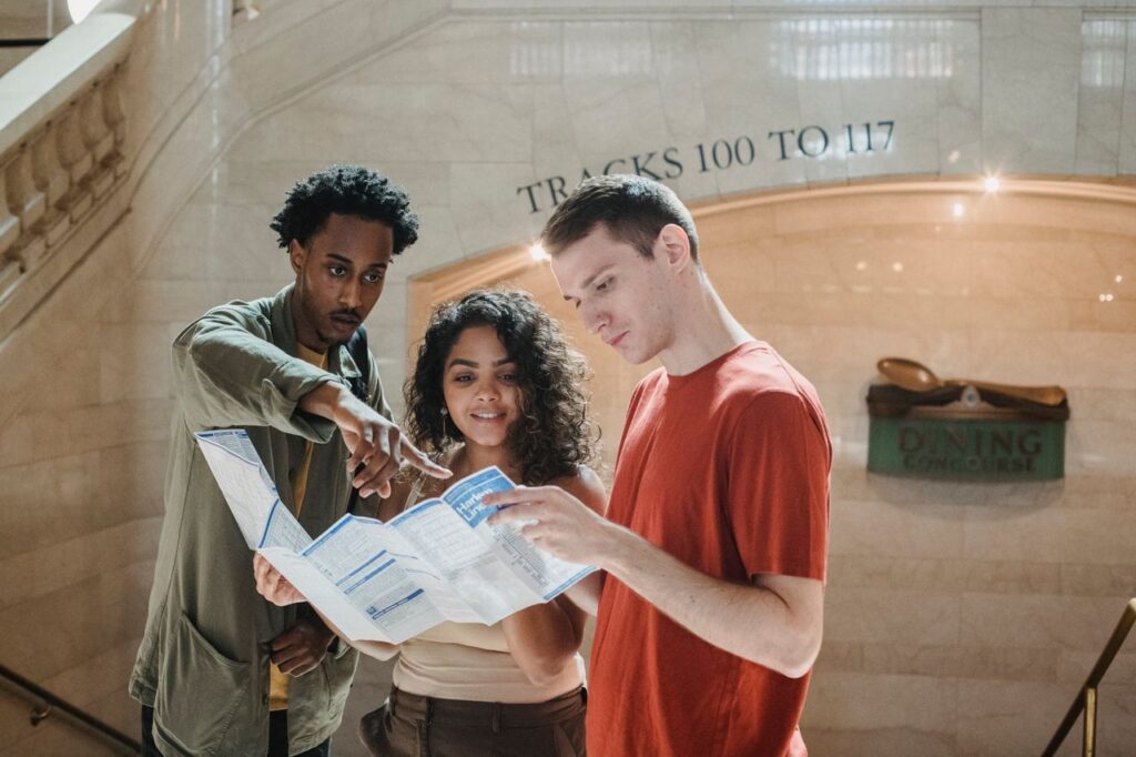 pexels-photo-6140459-6140459 Serious young black guy pointing at map while standing in Grand Central Terminal with multiethnic classmates