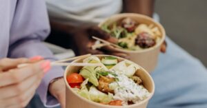 Two people enjoying nutritious salad bowls with fresh ingredients indoors.