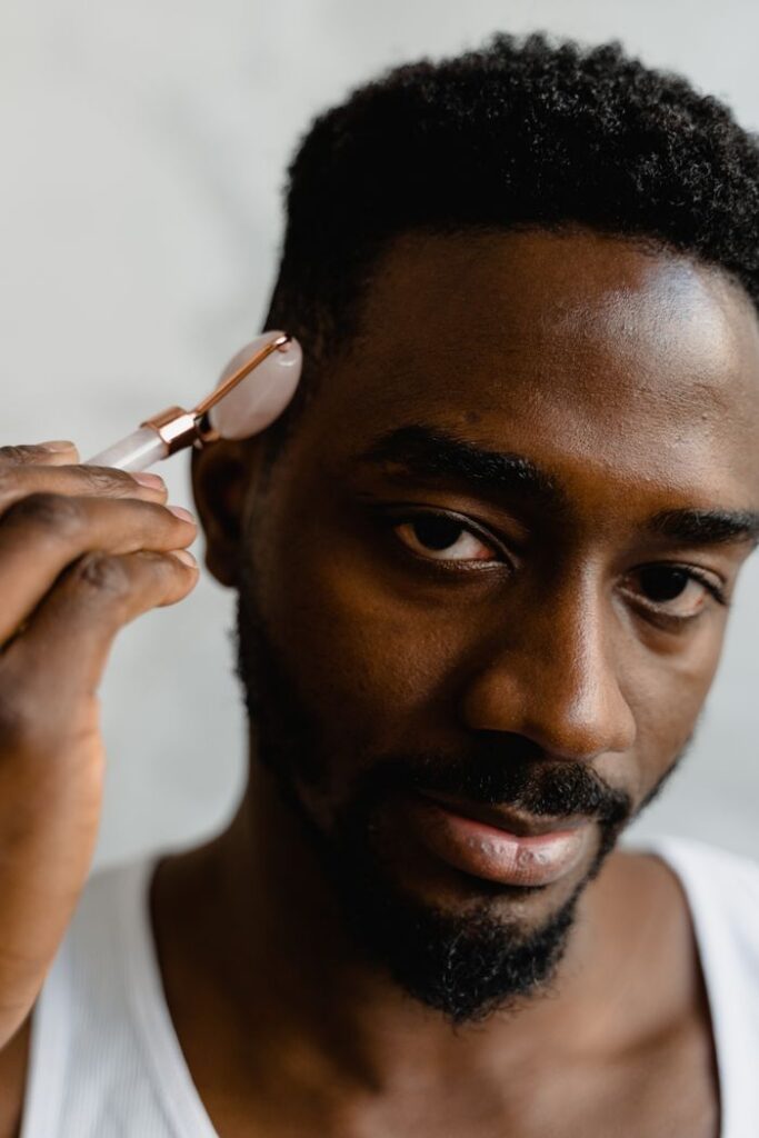 Close-up of a man using a jade roller on his face for skincare routine.