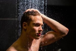 Portrait of a handsome man under a shower, highlighting water droplets and a pensive expression.