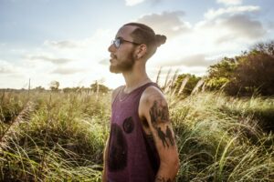 A bearded man with tattoos enjoys a sunny day in a Uruguayan field.