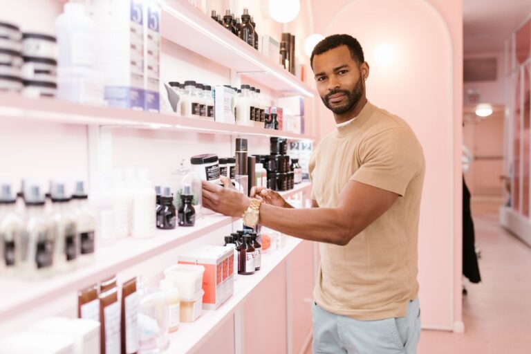 Confident man exploring a variety of beauty products in a stylish beauty salon.