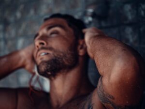 Close-up of a muscular, tattooed man enjoying a refreshing shower.