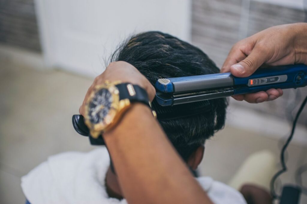 pexels-photo-3916358-3916358 Close-up of a hairdresser styling a client's hair using a straightener in a barbershop.