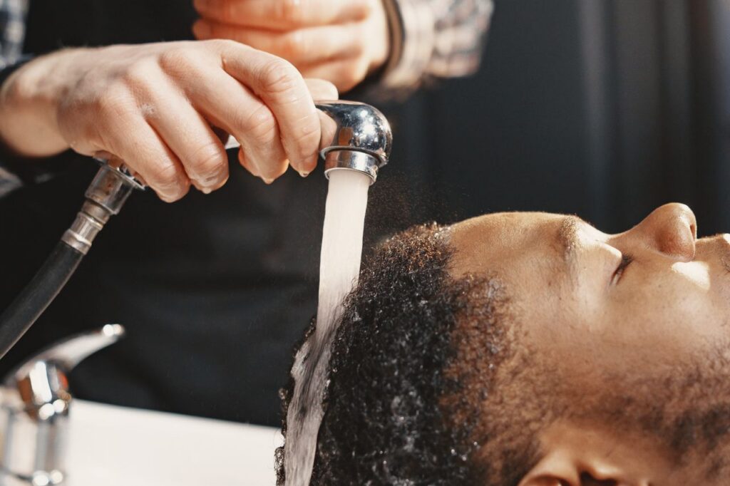 Close-up of a man receiving a professional hair wash at a salon.